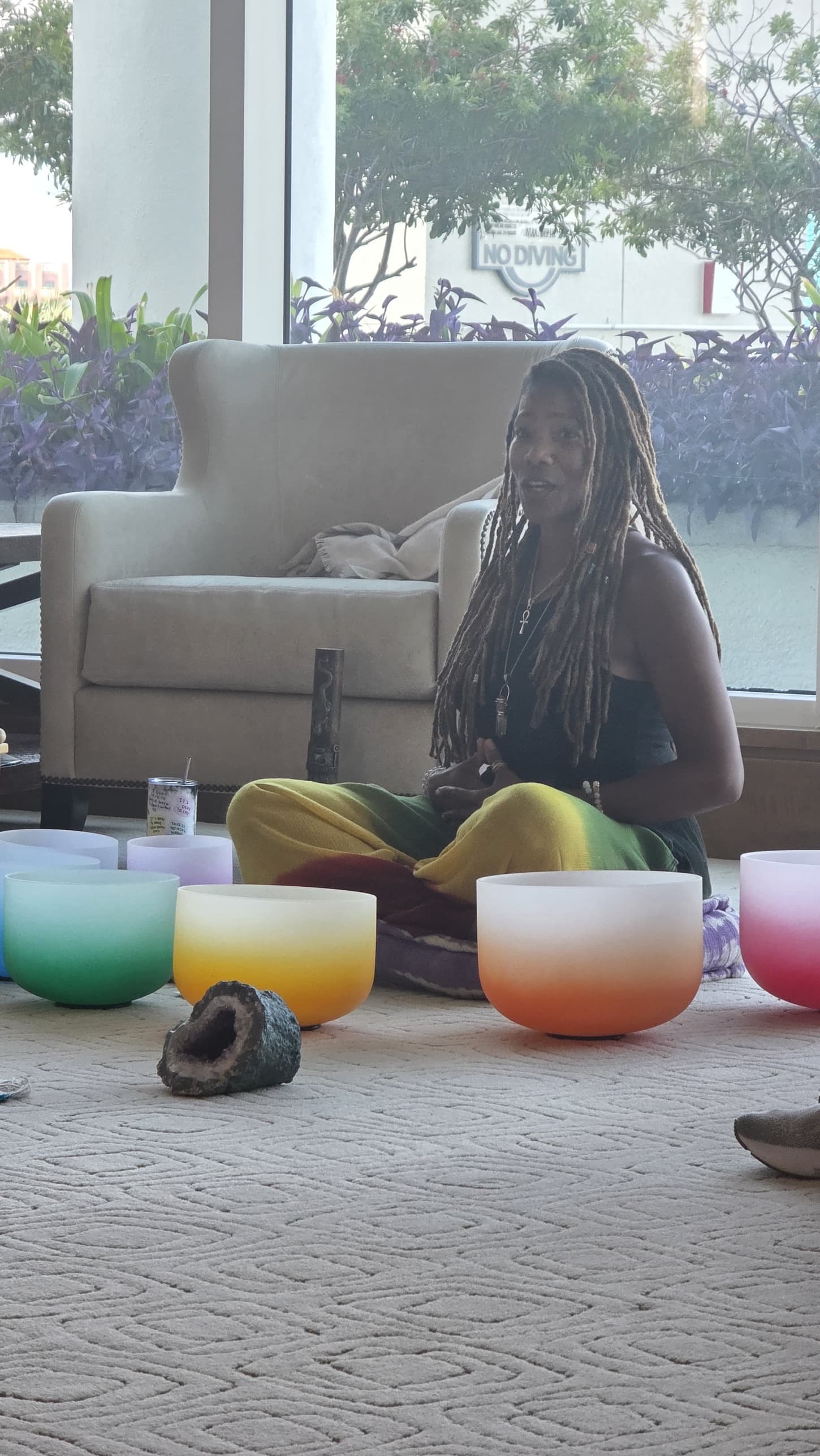 Malinda D. Ellis seated among crystal singing bowls, leading a sound bath session