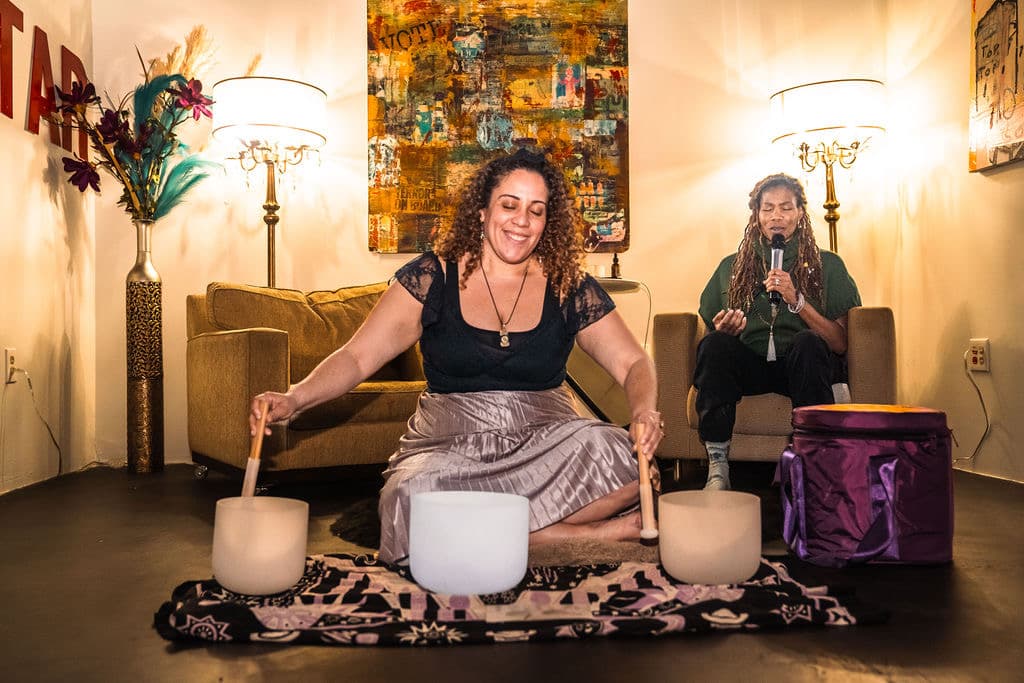 Malinda speaking into a microphone during a live sound healing session